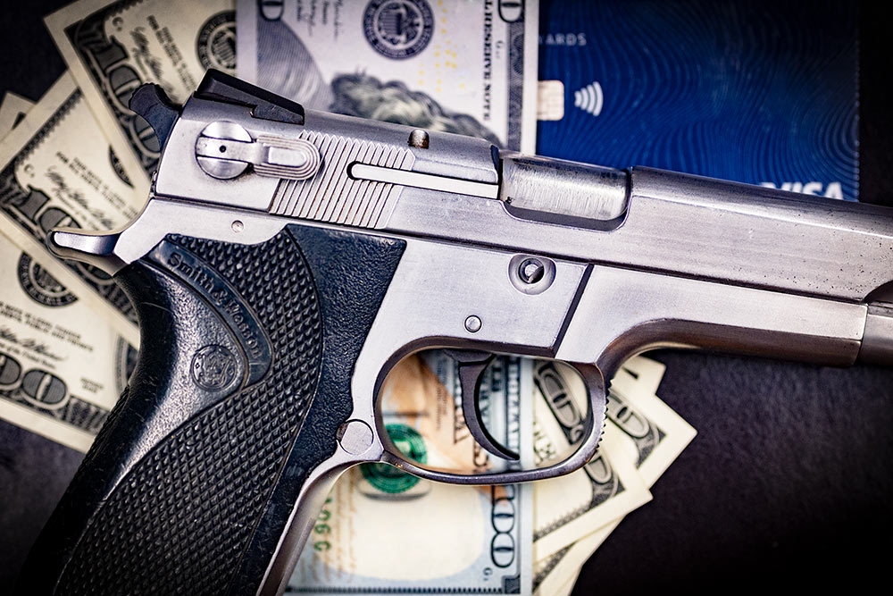 A photo of a handgun with money representing the credit card gun registry scheme. Photo credit to Jim Grant