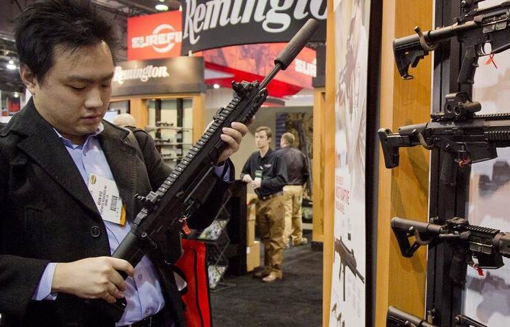 Photo of a person inspecting a rifle at what looks like a gun show
