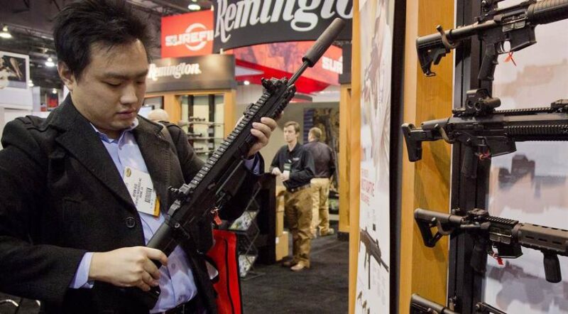 Photo of a person inspecting a rifle at what looks like a gun show