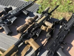 Rifles laying on a wood table outside.