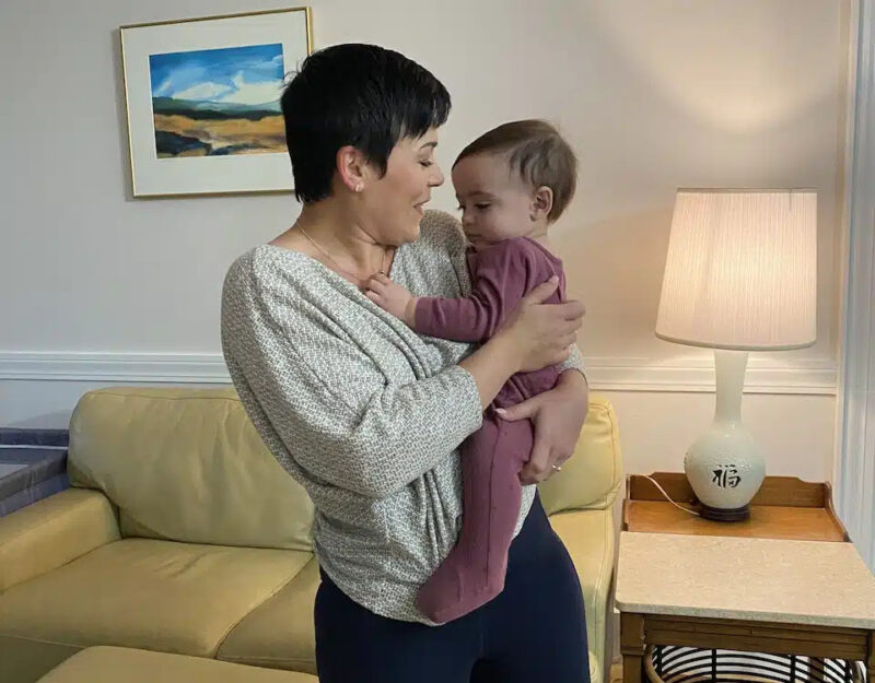 Tatiana Whitlock holding her baby in a living room setting